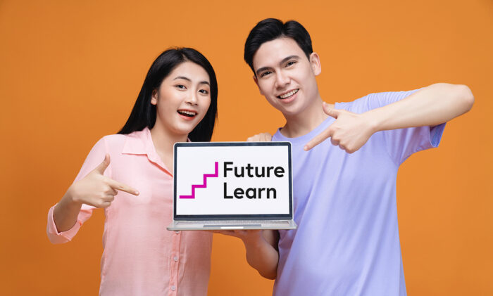 Promotional image for FutureLearn. young Asian couple holding laptop displaying the FutureLearn logo.