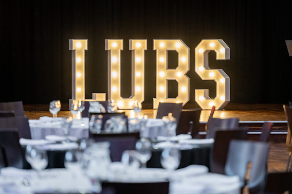 The letters L U BS is glowing light up bulbs on stage at the event